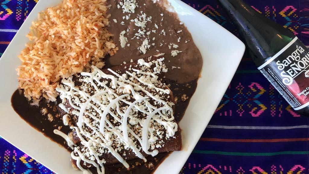 Enchiladas De Mole · Three rolled corn tortillas stuffed with shredded chicken or cheese smothered in our sweet mole sauce topped with Cotija cheese, onions and sour cream. Served with a side of rice and refried beans.