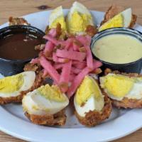 Scotch Eggs · 2 jumbo hard boiled eggs wrapped in our chorizo breading, deep fried & then drizzled w/ a du...