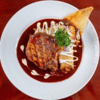 Chuleta De Puerco · Grilled pork chop in guajillo sauce served with two pork tamales rojos drizzled with sour cr...