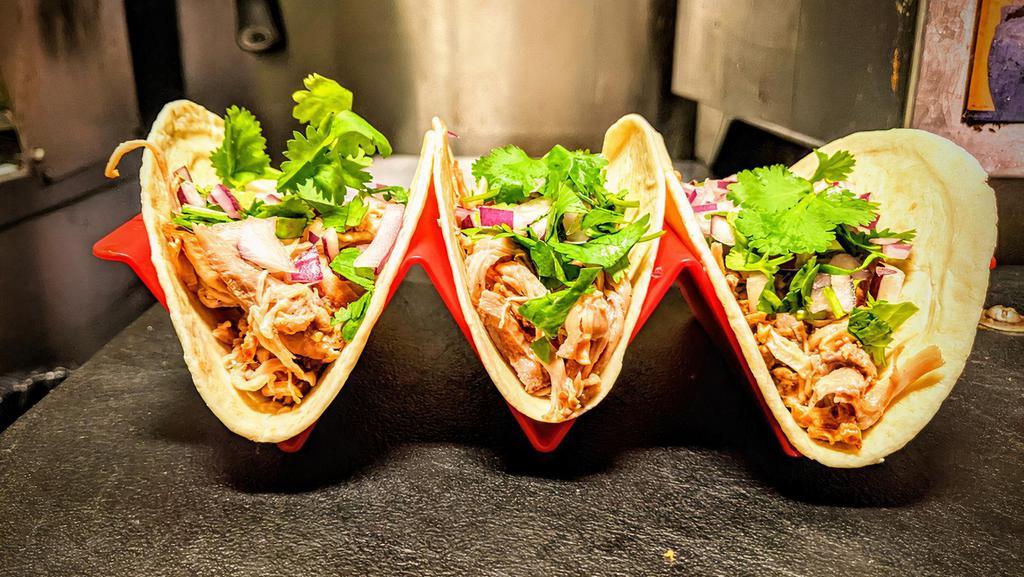 Carnitas Tacos · Sweet and spicy slow cooked pulled pork topped with fresh diced red onions and cilantro.