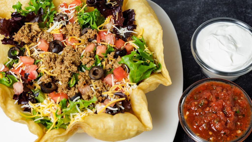 Taco Salad · Seasoned beef or chicken, cheddar jack cheese, tomatoes, and black olives in a fried tortilla bowl. Served with salsa, sour cream, and choice of dressing.