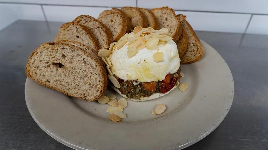 Cheese Torte · Cream cheese and goat cheese layered. with pesto and sun-dried tomatoes.. Topped with toasted almonds and served. with brown bread crostini