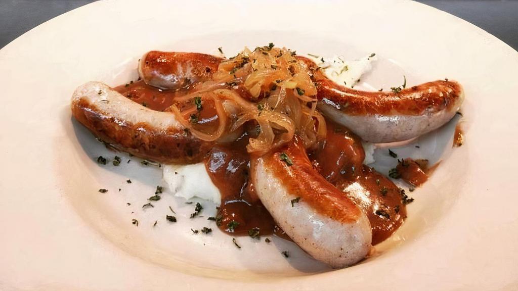 Bangers And Mash · Four Irish sausages (bangers) served with. a generous portion of champ, topped with. caramelized onions and rich Guinness gravy.. Served with fresh sautéed vegetables