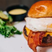 Hangover Burger · Topped with a fried egg, bacon, American cheese, and a side of hollandaise sauce. Served on ...