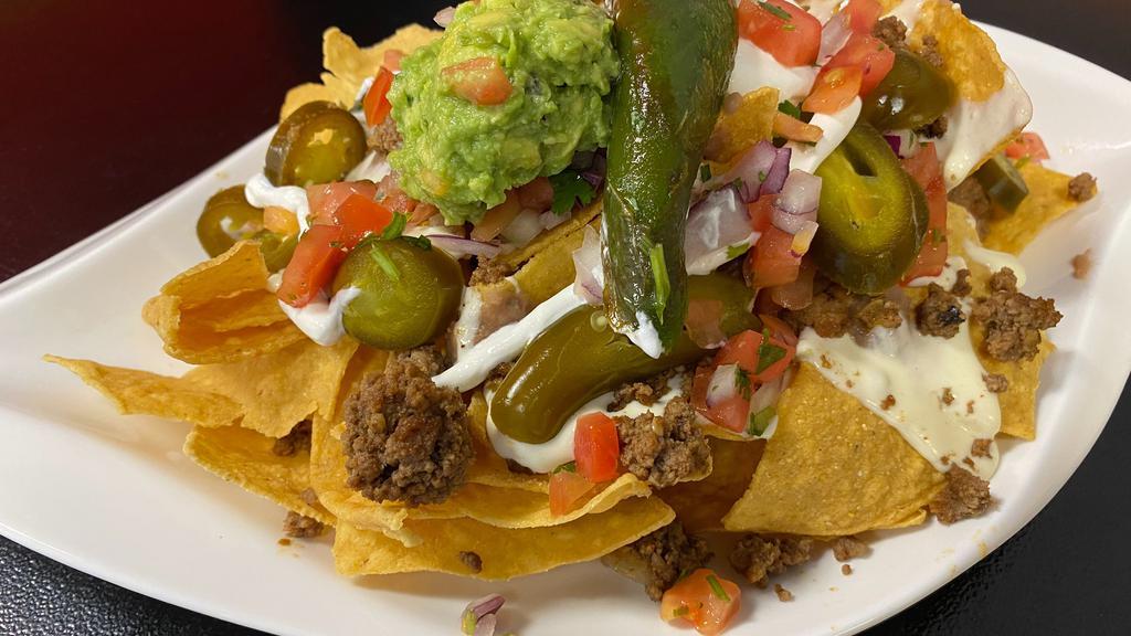 Nachos · Crispy corn chips with your choice of meats, carnitas, asada, alpastor, chicken, ground beef, topped with cheese , pico, jalapenos, refried beans, sour cream, guacamole.