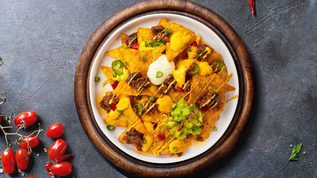 Nacho Supremacy · Salted tortilla chips doused in melted nacho cheese and topped with ground beef, jalapenos, pinto beans, sour cream, and avocado.