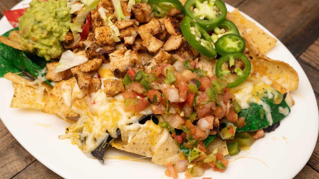 Ultimate Chicken Nachos · Layers of rainbow tortilla chips smothered with cheese sauce, guacamole, sour cream, jalapeno peppers and our homemade pico de gallo.