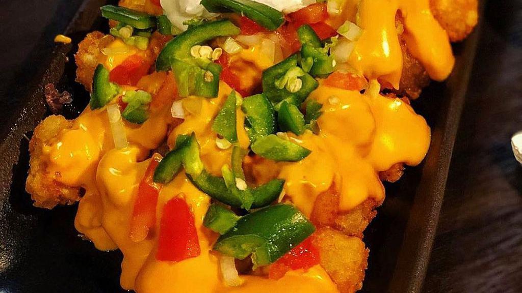 Totchos · Crispy tater tots topped with Cheddar cheese sauce, tomatoes, onions, black olives, jalapenos, and sour cream.