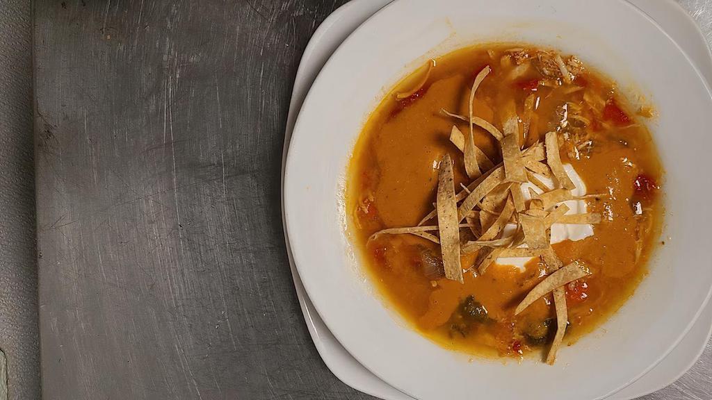 Tortilla Soup · A cup of tomato soup mixed with shredded chicken. Topped with tortilla strips and sour cream