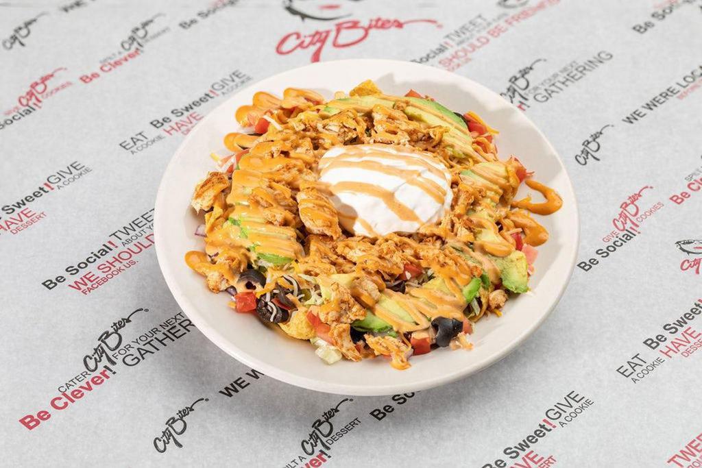 Baja Chicken Salad · Fritos® corn chips, seasoned grilled chicken, shredded lettuce, tomatoes, red onions, black olives, shredded cheddar, topped with sour cream, sliced avocado, and chipotle sauce
