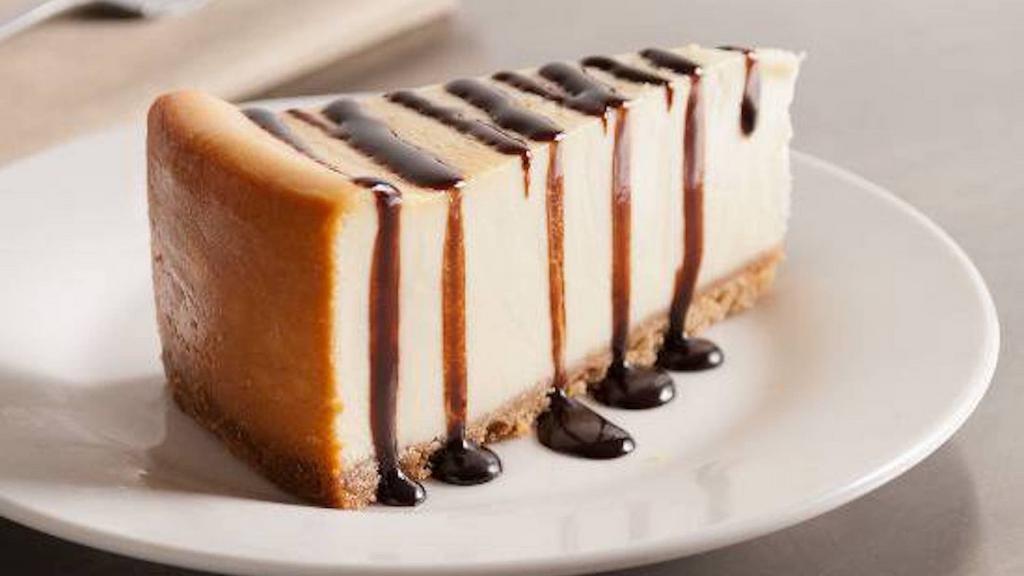 Cheesecake · Slice of New York style cheesecake topped with chocolate sauce.