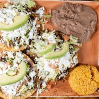 Tostada · Tostada topped with refried beans, lettuce, tomatoes, sour cream, avocado slice, and queso, ...
