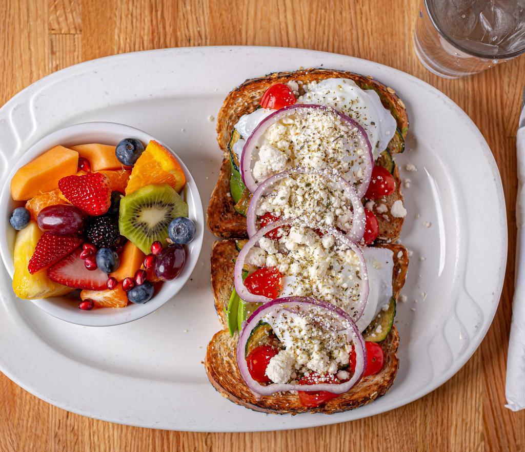 Avocado Feta Toast · Choice of toast topped with freshly smashed avocado, grilled zucchini, imported feta cheese, cherry tomatoes, red onions, poached eggs, drizzled with extra virgin greek olive oil + sprinkled with oregano