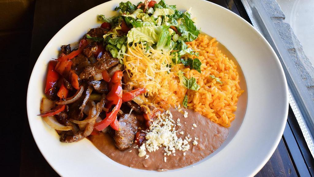 Steak Fajita Bowl · Marinated flank steak/ grilled poblano/ pepper and onions/cilantro and onion/house-made rojo sauce/queso fresco/rice/colby jack cheese/refried pinto beans/sour cream
