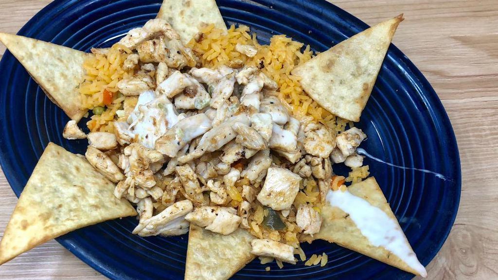 Arroz Con Pollo · Bed of rice with cheese sauce on the top and grilled chicken.