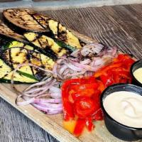 The Grilled Garden · Wood-fire roasted red onions, zucchini, eggplant, and red peppers served with house-made gar...