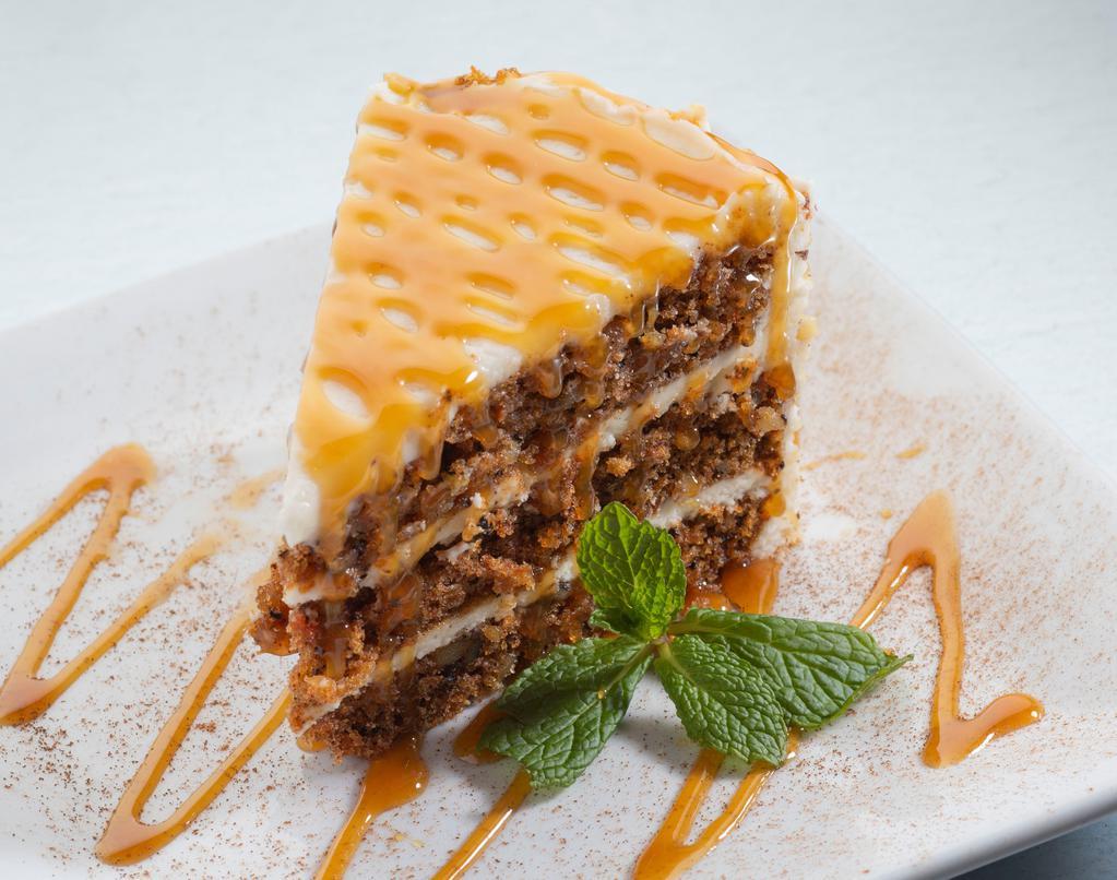 Carrot Cake · Three towering layers of our own special recipe with thick, velvety cream cheese icing, drizzled with caramel sauce.