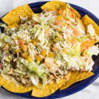 Nachos Al Carbón · Steak, chicken, shrimp, pico de gallo, lettuce, and cheese sauce served with chips.