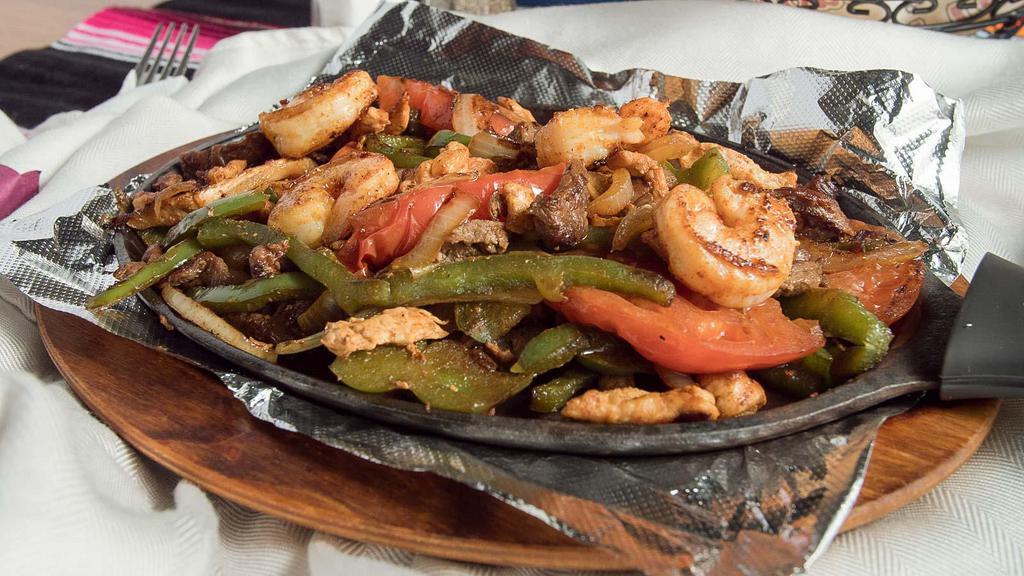 Texas Fajita · A delicious combination of steak, shrimp, chicken and Mexican sausage grilled to perfection with onions, bell peppers, tomatoes and zucchini. Comes with soft flour tortillas, pico de gallo, sour cream, beans, rice, and guacamole. Served on a sizzling plotter.
