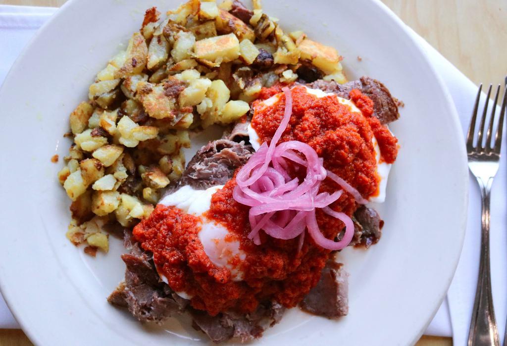 Irish Benedict · Fresh-braised sliced corned beef, poached eggs, pickled red onion on top of marble rye bread, topped with our red roasted pepper sauce