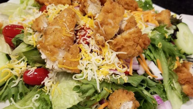 Fried Chicken Salad · Fried chicken tenders over mixed greens, cherry tomatoes, cucumbers, cheddar jack, red onion and carrots with a side of buttermilk ranch.