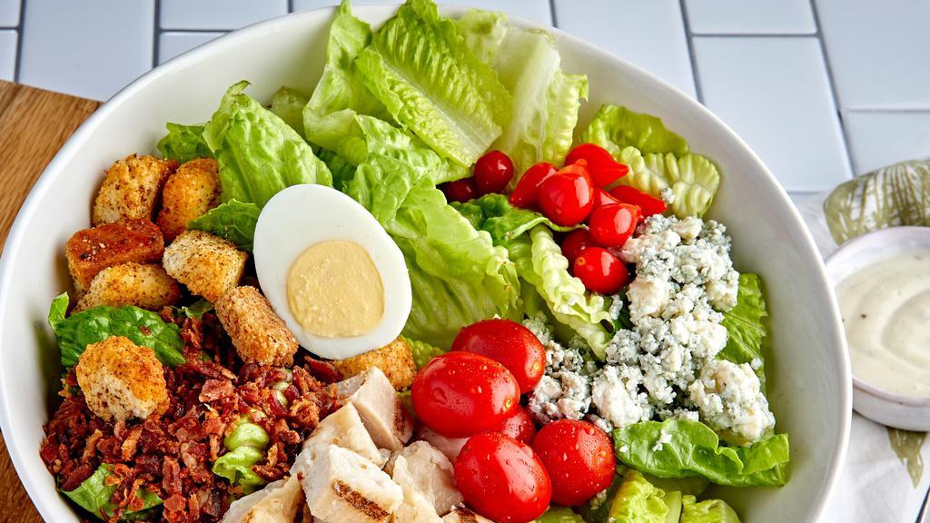 Cobb Salad With Grilled Chicken · Chopped Romaine, Tomatoes, Egg, Bacon, Blue Cheese, Tear Drop Peppers, topped with Grilled Chicken, Ranch Dressing on side.