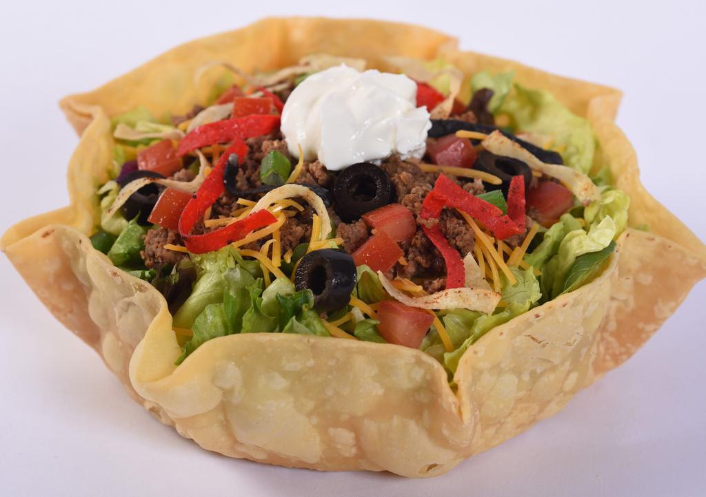 Taco Salad · Lettuce blend, seasoned ground beef, cheddar cheese, black olives, green onions, and tomatoes served in fresh, crisp tortilla bowl topped with sour cream and tortilla strips.