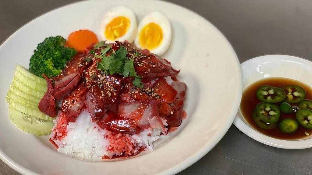 Honey Grazed Bbq Pork On The Rice · Classic street food in Thailand.  Our homemade BBQ pork, white rice, boiled egg tossed with delicious pork gravy and sesame seed.  Garnished with cucumber, fresh green onion and served with jalapeno soy sauce.