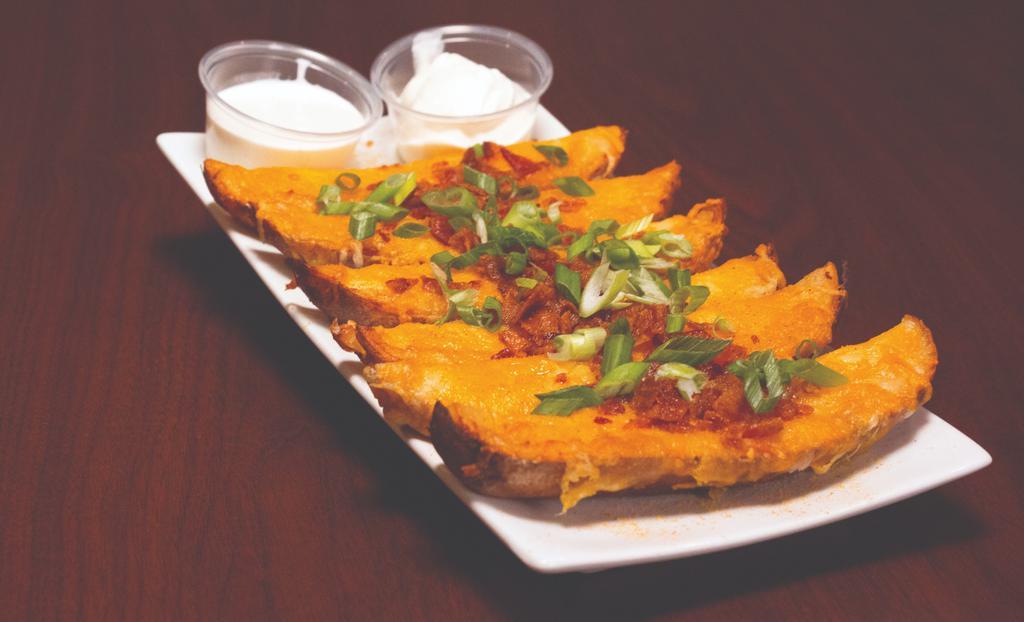 Corral Skins · Crispy potato skins smothered with Monterey jack and cheddar cheeses, bacon and green onions. Served with ranch for dipping and sour cream on the side.