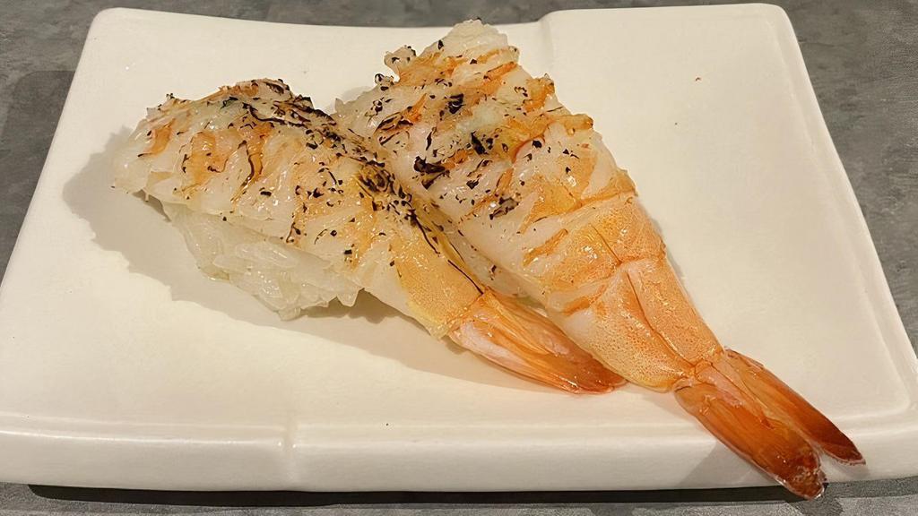 Garlic Butter Shrimp Nigiri · Two pieces of cooked shrimp nigiri sushi with garlic butter on top and torched.