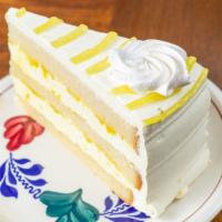 Lemoncello Layer Cake Slice · Vanilla sponge cake, layered with limoncello mousse, topped with lemon flavored whipped crea...