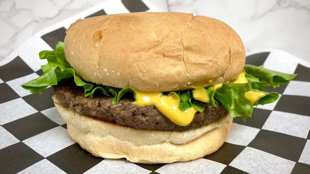 Impossible Burger · Vegan burger patty with lettuce and yellow mustard, grilled on a bun.