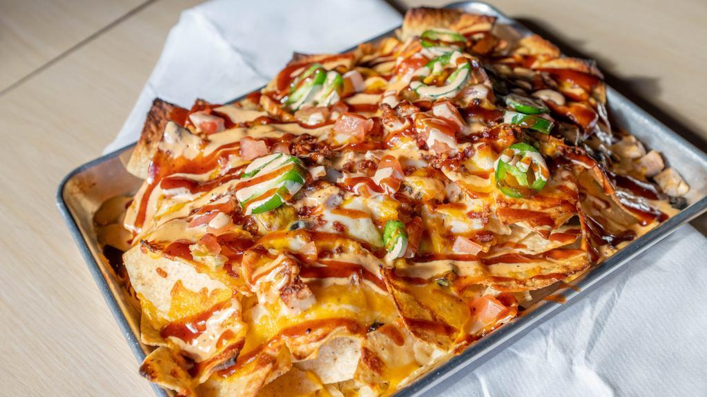 Grilled Chicken Nachos · Four cheeses, bacon crumble, black olives, tomatoes, fresh jalapeños, bourbon BBQ & Shakers sauce drizzle.