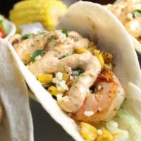 Elote Shrimp Tacos · Three tacos with grilled shrimp, roasted elote corn, shredded lettuce, cotija cheese, and ci...