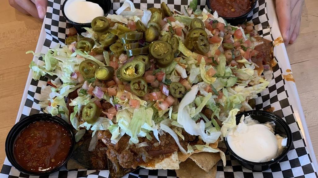 Deluxe Nachos · Crisp corn tortilla chips with nacho cheese sauce, lettuce, tomato, black olives, jalapeños, sour cream. salsa and your choice of chicken or chili.