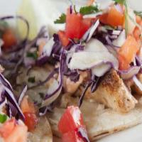 Fish Tacos · Three Tacos on Corn Tortillas, Topped with Chipotle Aioli Sauce, Red Cabbage, Tomato, Cilant...