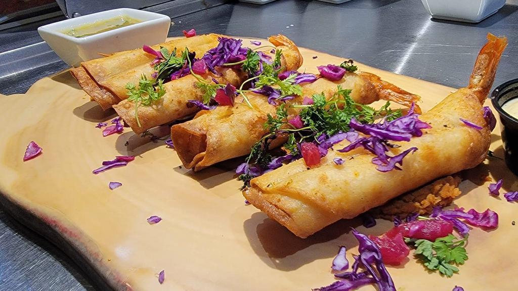 Shrimp Rolled Taquitos · Shrimp wrapped in a corn tortilla and deep fried until golden brown served with red cabbage salad, guacamole and microgreens.