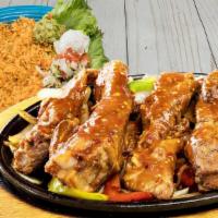 Ribs Fajitas Costillas · Pork ribs with red or green sauce, bell peppers and onions. Served with guacamole, sour crea...