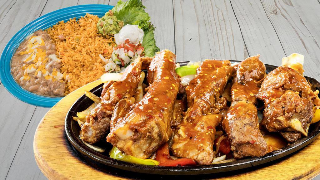 Ribs Fajitas Costillas · Pork ribs with red or green sauce, bell peppers and onions. Served with guacamole, sour cream, pico de gallo and two sides.