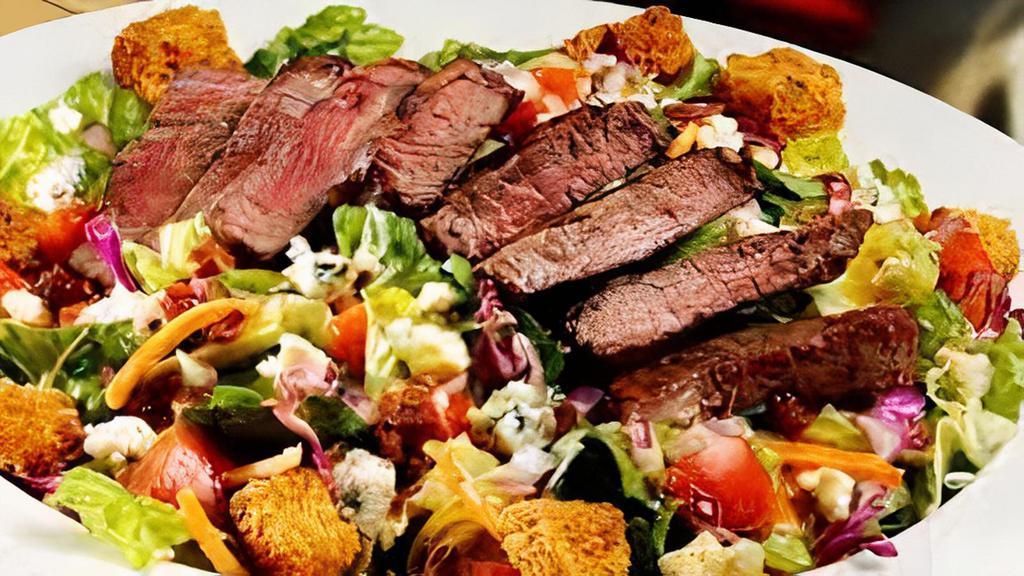 Steakhouse · Salad or roasted tomato wrap with seared flat iron steak, sweet red peppers, slow roasted yellow tomatoes, roasted potatoes, scallions, aged white cheddar, crispy onion strings and romaine lettuce served with red wine vinaigrette.