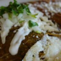 Chilaquiles · Two eggs served over-easy atop warm tortilla chips, rice and beans, diced onions. Topped wit...