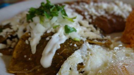 Chilaquiles · Two eggs served over-easy atop warm tortilla chips, rice and beans, diced onions. Topped with homemade salsa Verde and queso fresco
