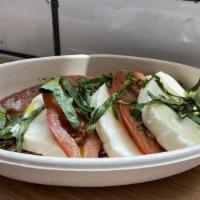 Caprese Salad · Heirloom tomatoes layered with fresh mozzarella and topped with freshly sliced basil and ext...