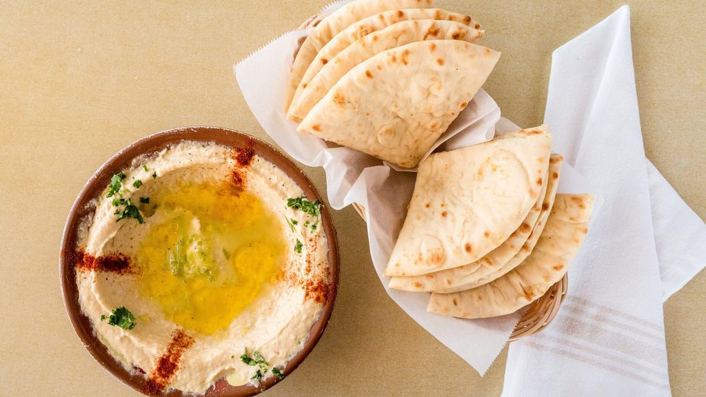 Hummus · Smooth dip of garbonzo beans, tahini sauce and garlic. Topped with olive oil and served with two hot pita bread.
