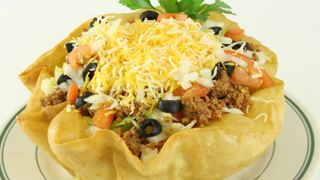 Taco Salad · A homemade taco bowl filled with crisp lettuce, taco meat, a blend of shredded cheeses, diced tomatoes, diced onions, black olives, sour cream, and salsa.