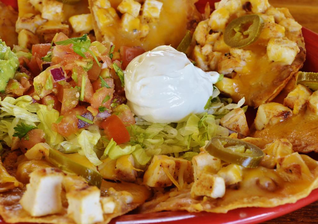 Fajita Nachos · Grilled chicken or steak layered on corn tortillas topped with cream cheese, refried beans, Monterey Jack and Cheddar cheeses and jalapeños, served with sour cream, guacamole, lettuce and pico de gallo.