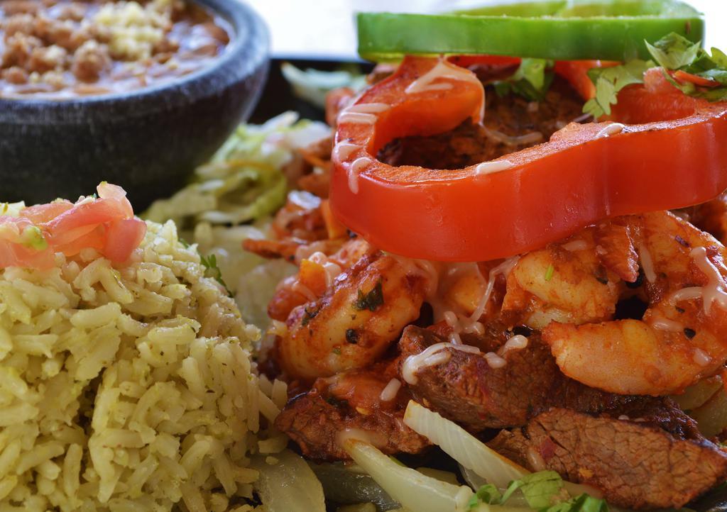 Mi Casa Fajita · Steak, chicken, shrimp, and chorizo sausage all grilled together on top a bed of grilled onions then topped with red and green peppers. Served with pico de gallo, guacamole, sour cream, charro beans and rice ¡perfecto!