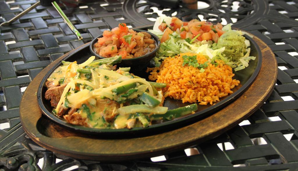 Fiesta Fajita · Grilled, marinated steak and chicken fajita with onions, jalapeños, tomatoes, fresh garlic, and cilantro in a real butter sauce. Served with lettuce, guacamole, sour cream, fresh flour tortillas, poblano rice and charro beans.
