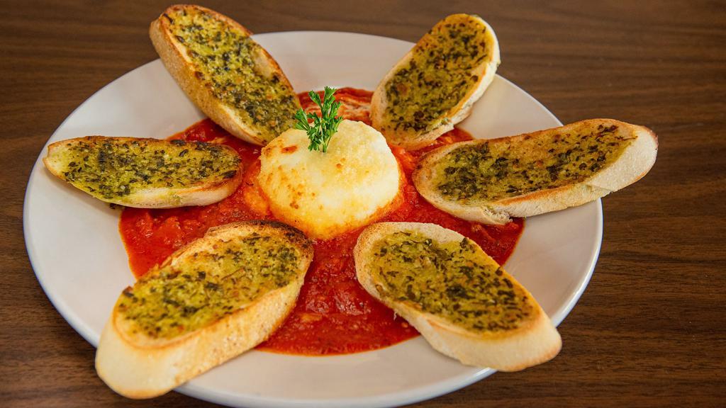 Baked Goat Cheese · Goat cheese baked in a bed of marinara served with pesto toast points