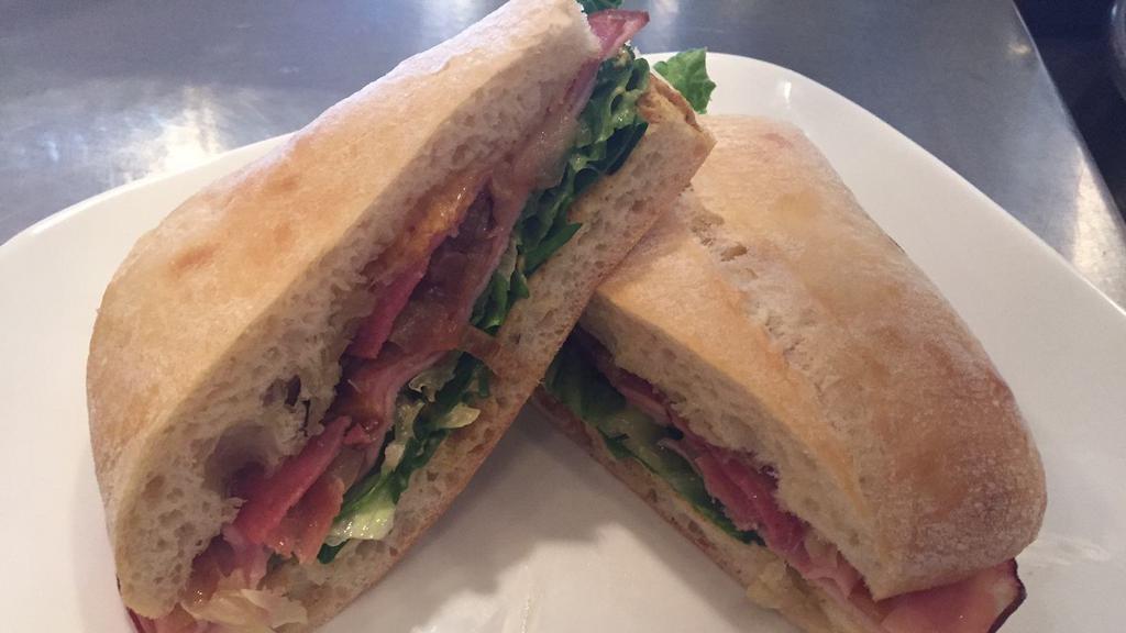 Ham Ciabatta · Smoked ham, salami, prosciutto with tomato, roasted onions, forest greens, cheddar cheese, swiss cheese, and whole grain mustard.